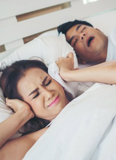 Persona tapándose los oídos por los ronquidos